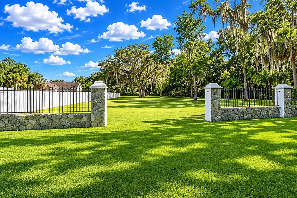 A grassy lot features a stone-based fence with iron railings and a wide gated entrance — RIVERVIEW DRIVE, RIVERVIEW, FL