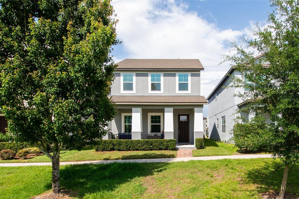 A two-story gray house with a front porch, white columns, and a manicured hedge — 2241 WHITE FEATHER LOOP, OAKLAND, FL