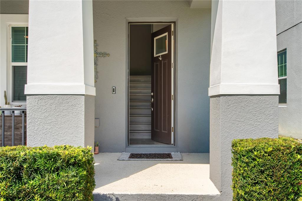 A front porch with a dark brown door leads into a home with interior stairs — 2241 WHITE FEATHER LOOP, OAKLAND, FL