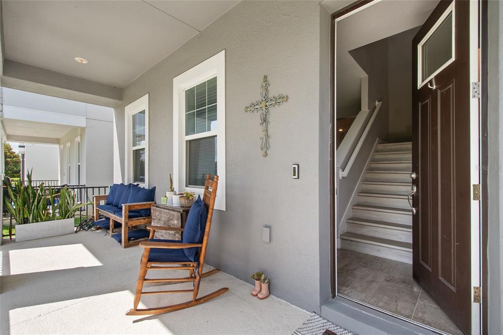 A covered front porch features a wooden rocking chair, a bench, and an open front door — 2241 WHITE FEATHER LOOP, OAKLAND, FL