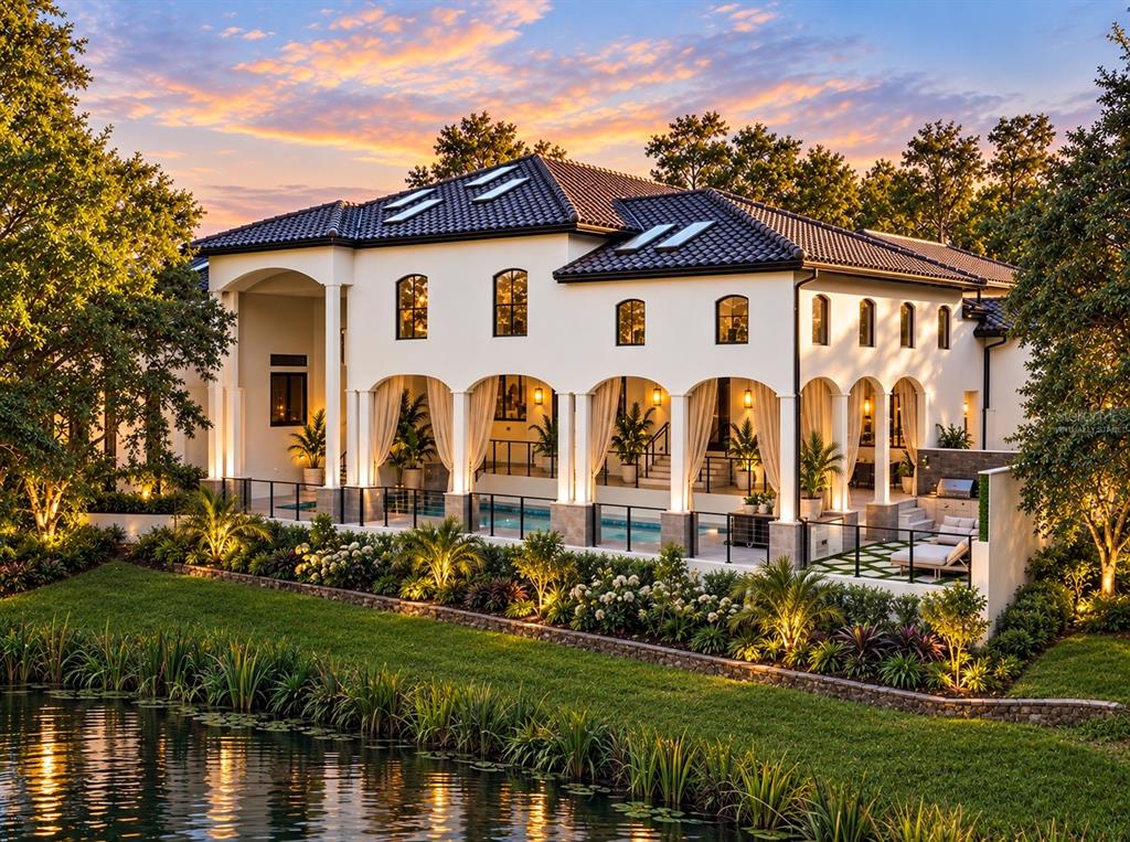 A two-story white stucco house with a tiled roof sits beside a pond with fountains — 9725 CHESTNUT RIDGE DRIVE, WINDERMERE, FL