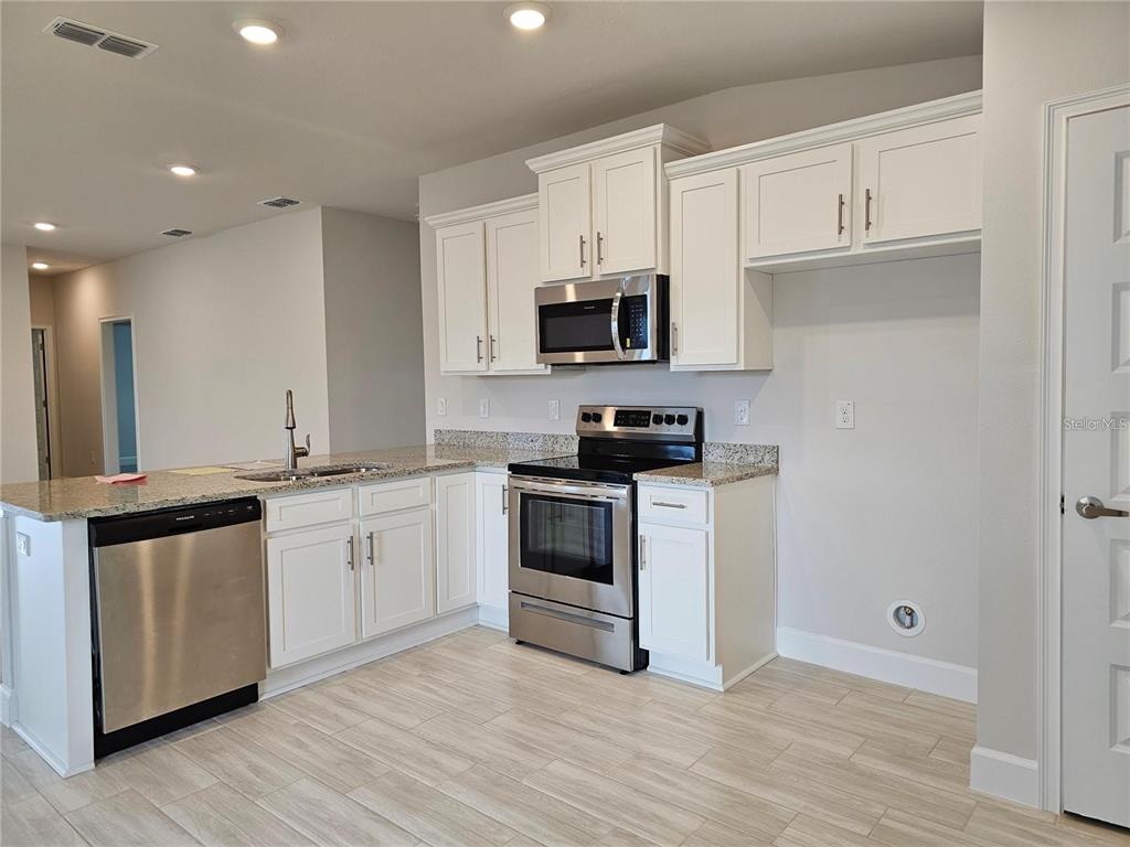 A kitchen featuring white cabinets, stainless steel appliances, and granite countertops — 36109 TRINITY GLADE ROAD, DADE CITY, FL