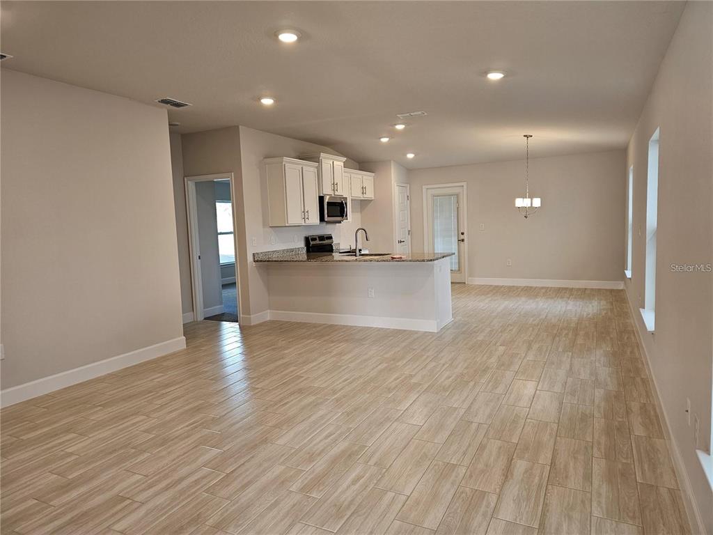 An open-concept kitchen features white cabinets, granite countertops, and light wood-look tile flooring — 36109 TRINITY GLADE ROAD, DADE CITY, FL