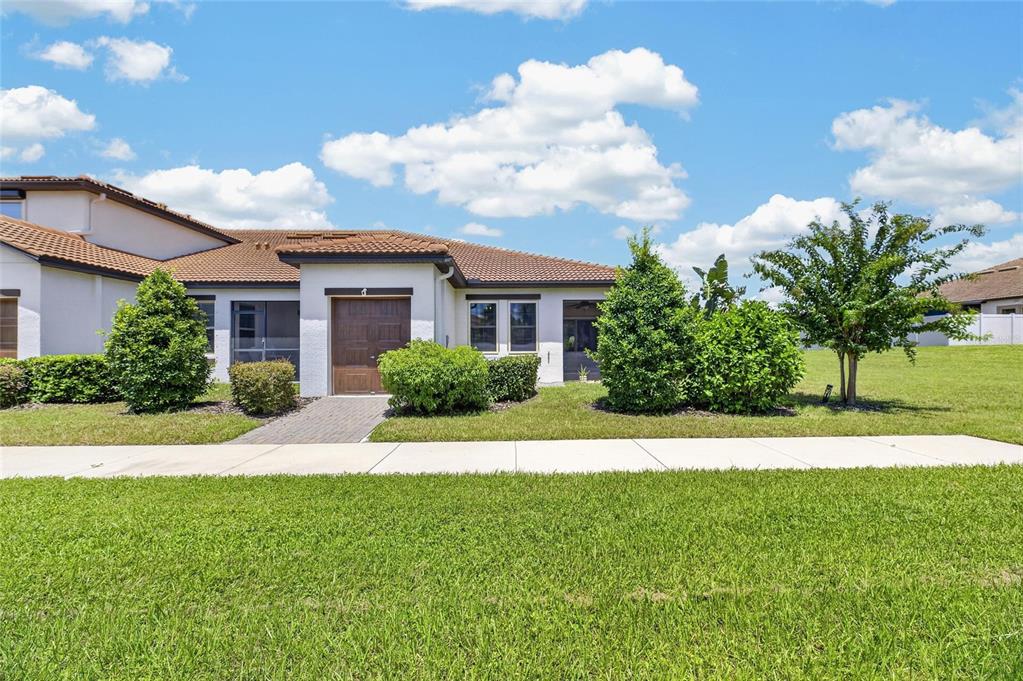 A single-story house with a brown tile roof, a wooden front door, and green landscaping — 5325 STOIC VALE DRIVE, WIMAUMA, FL