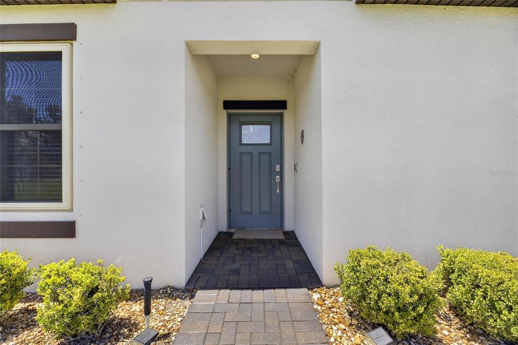 A front entryway with a blue door, a stone walkway, and small green shrubs — 5325 STOIC VALE DRIVE, WIMAUMA, FL