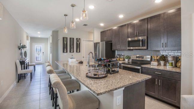 A kitchen features dark wood cabinets, granite countertops, a large island with seating, and tile flooring — 25474 CALUSA DRIVE, PUNTA GORDA, FL