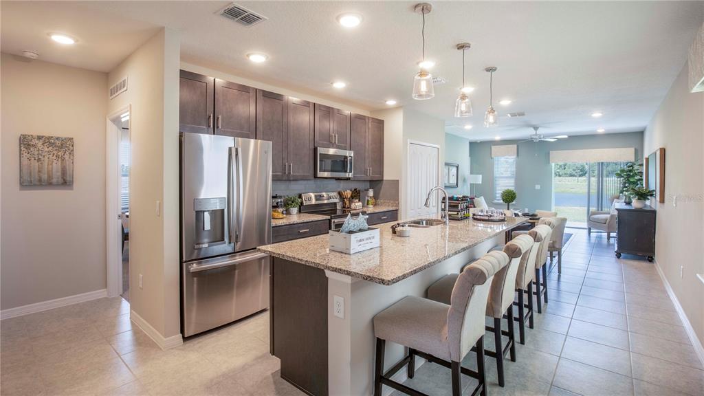 A kitchen with dark cabinets, granite countertops, a large island, and stainless steel appliances — 25474 CALUSA DRIVE, PUNTA GORDA, FL