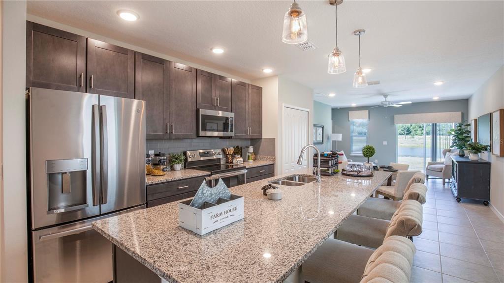 A kitchen with dark cabinets, granite countertops, a large island, and stainless steel appliances — 25474 CALUSA DRIVE, PUNTA GORDA, FL