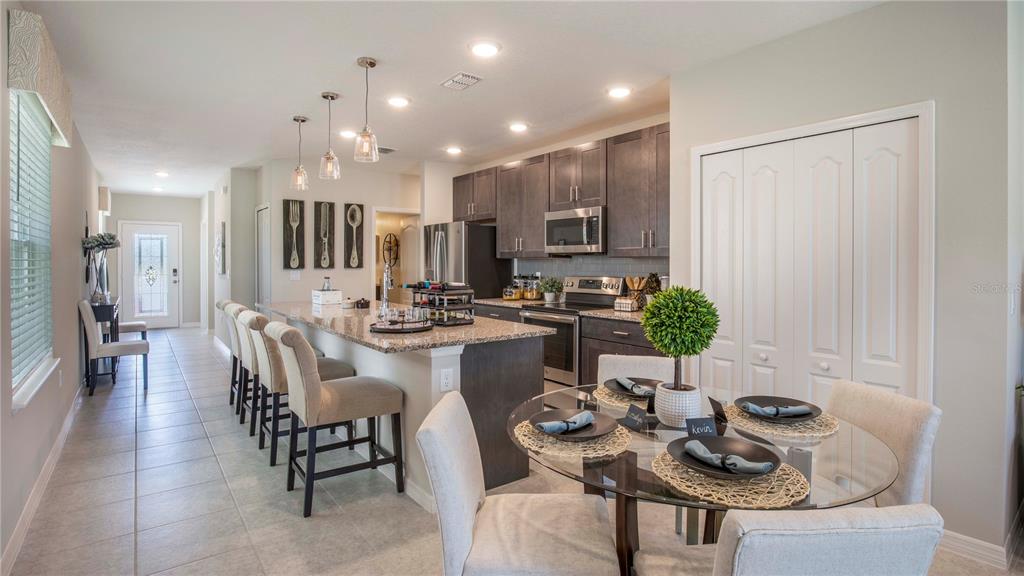 A kitchen with dark cabinets, granite countertops, a breakfast bar, and a glass dining table — 25474 CALUSA DRIVE, PUNTA GORDA, FL