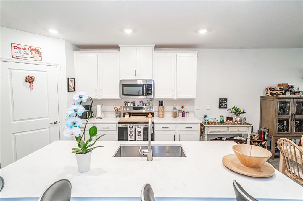 A kitchen features white cabinets, a central island with a sink, and stainless steel appliances — 10857 RUSTIC EVE COURT, LAND O LAKES, FL
