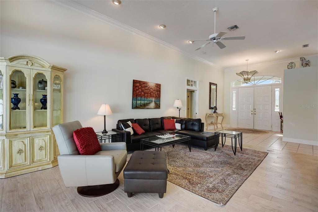 A living room features a black sectional sofa, a light-colored armchair, and tile flooring — 4653 HADFIELD DRIVE, SARASOTA, FL