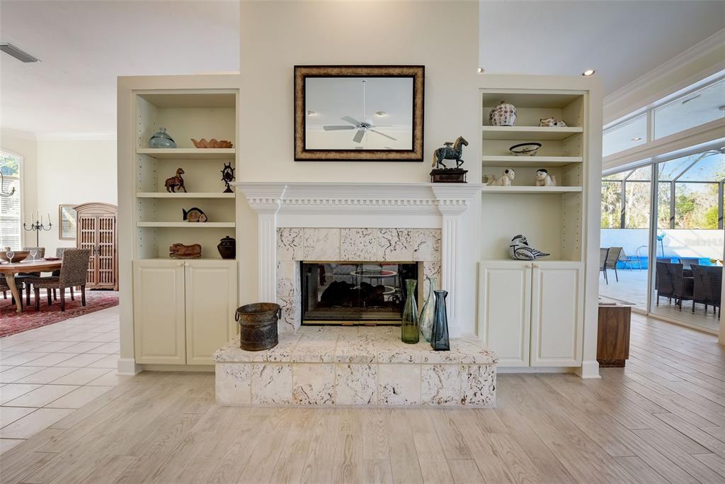 A living room features a stone fireplace flanked by built-in shelves and light wood flooring — 4653 HADFIELD DRIVE, SARASOTA, FL