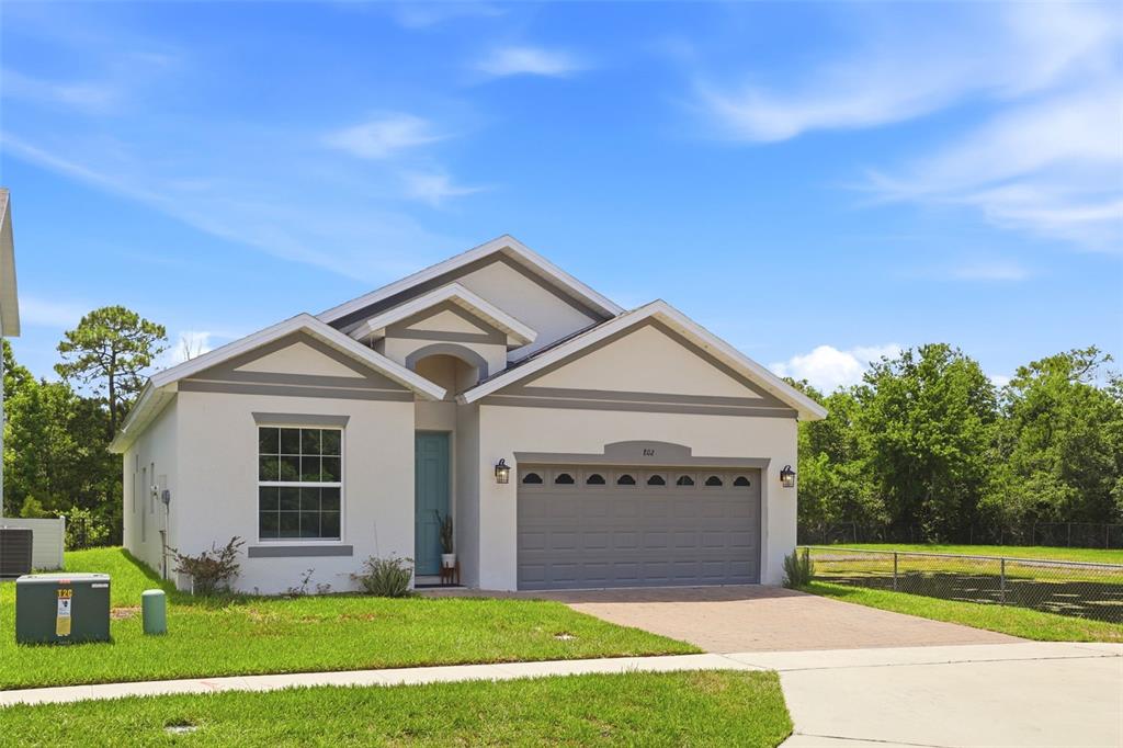 A single-story house with a white stucco exterior, gray trim, and a two-car garage — 802 REFLECTION LAKE DRIVE, ORLANDO, FL