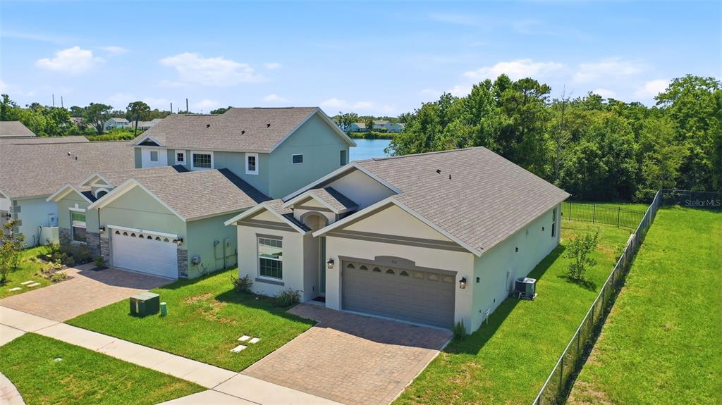 An aerial view shows a single-story house with a paved driveway and a fenced yard — 802 REFLECTION LAKE DRIVE, ORLANDO, FL