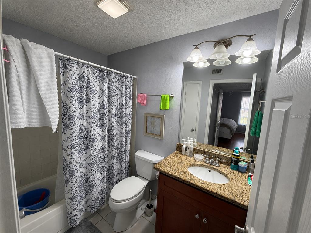 A bathroom features a shower-tub combo, a toilet, and a vanity with a granite countertop — 10200 GANDY BOULEVARD N UNIT 418, ST PETERSBURG, FL