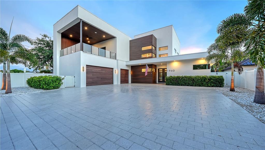 A modern two-story house with a paved driveway, wood-paneled garage doors, and a balcony — 1960 BOYCE STREET, SARASOTA, FL