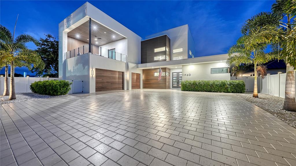 A modern two-story house with a paved driveway, wood accents, and palm trees at dusk — 1960 BOYCE STREET, SARASOTA, FL