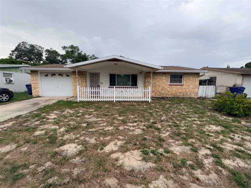 A single-story house with a stone facade, a white picket fence, and a garage — 3541 BIGELOW DRIVE, HOLIDAY, FL