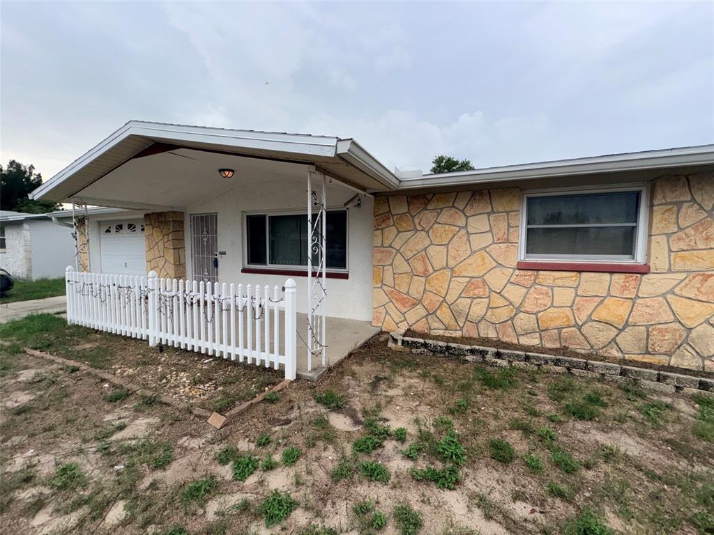 A single-story house with a stone facade, a white picket fence, and a covered porch — 3541 BIGELOW DRIVE, HOLIDAY, FL