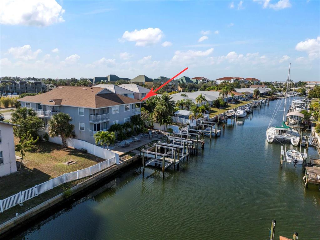 An aerial view of a multi-story apartment building situated along a canal with boat slips — 1013 APOLLO BEACH BOULEVARD UNIT 203, APOLLO BEACH, FL