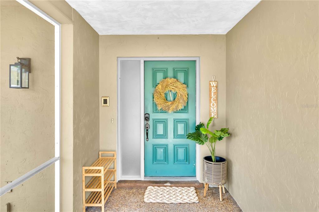 A teal front door with a wreath and a welcome sign sits on a covered porch — 2921 CAPTIVA DRIVE, SARASOTA, FL