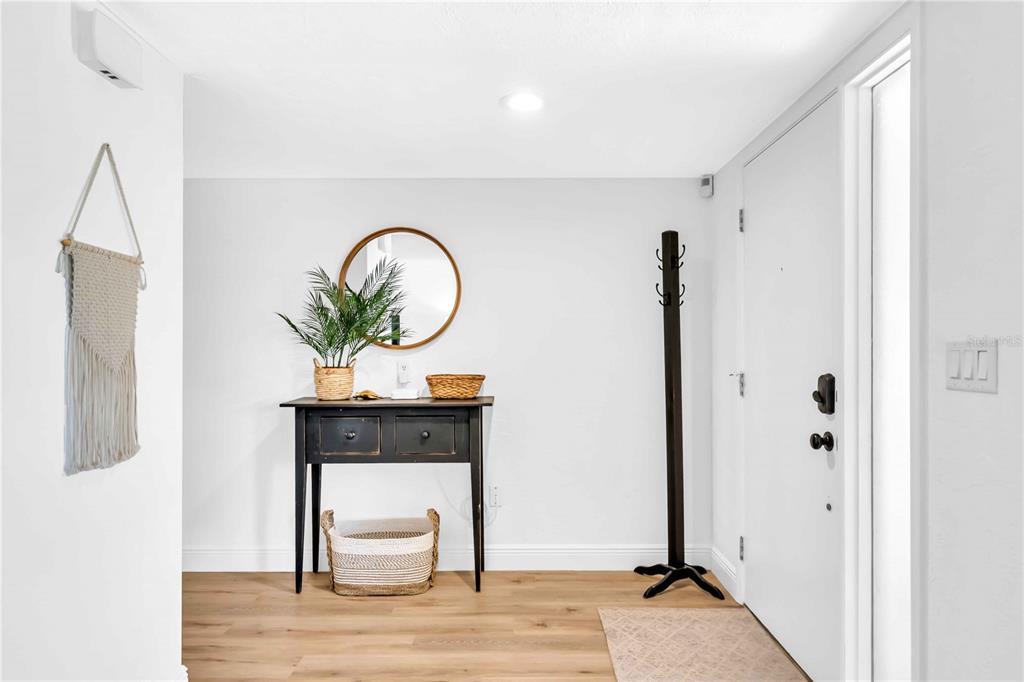 An entryway features a black console table, a round mirror, and a coat rack — 2921 CAPTIVA DRIVE, SARASOTA, FL