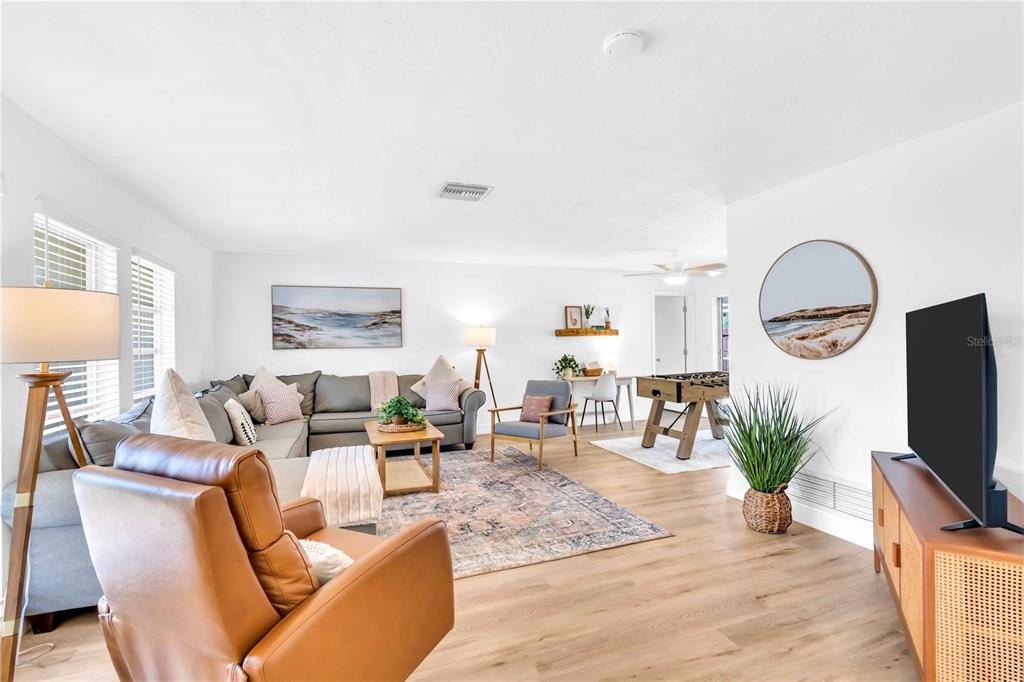 A living room features a sectional sofa, leather armchair, foosball table, and light wood flooring — 2921 CAPTIVA DRIVE, SARASOTA, FL