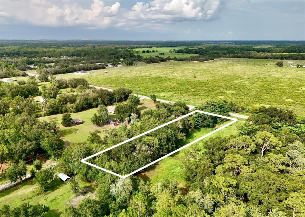 An aerial view shows a rectangular plot of land outlined in white amidst wooded terrain — MCCLELLAN ROAD, FROSTPROOF, FL