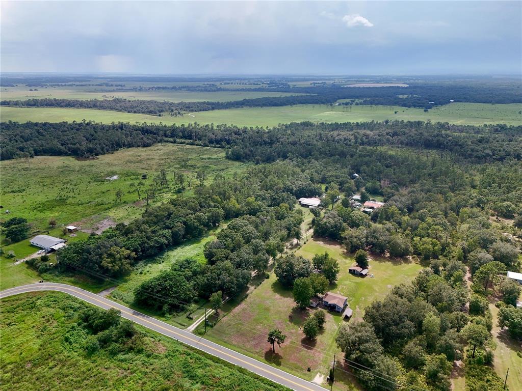 An aerial view shows a rural property with multiple houses, trees, and a paved road — MCCLELLAN ROAD, FROSTPROOF, FL