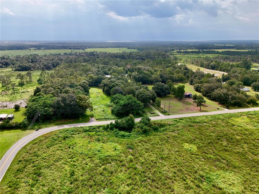 An aerial view shows a paved road curving through a rural landscape with scattered trees — MCCLELLAN ROAD, FROSTPROOF, FL