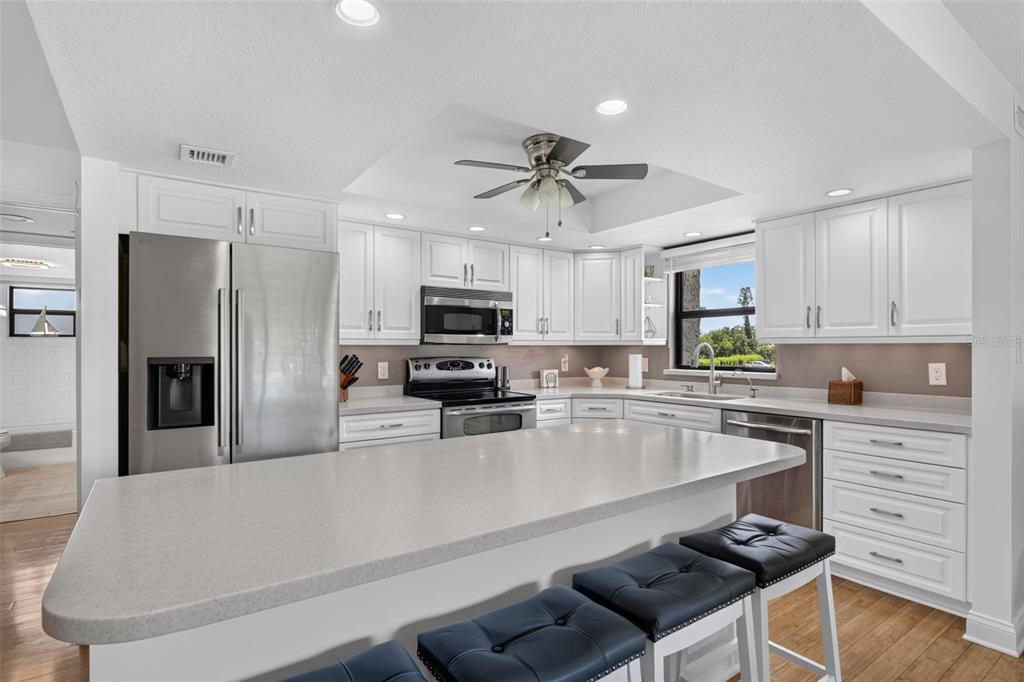 A kitchen with white cabinets, stainless steel appliances, a large island, and dark bar stools — 1610 ISLAMORADA BOULEVARD UNIT 61B, PUNTA GORDA, FL