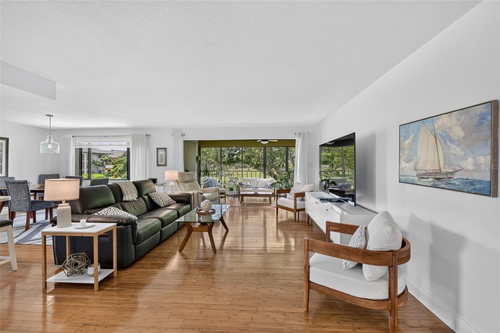 A living room with hardwood floors, a black leather sofa, and a view of a balcony — 1610 ISLAMORADA BOULEVARD UNIT 61B, PUNTA GORDA, FL