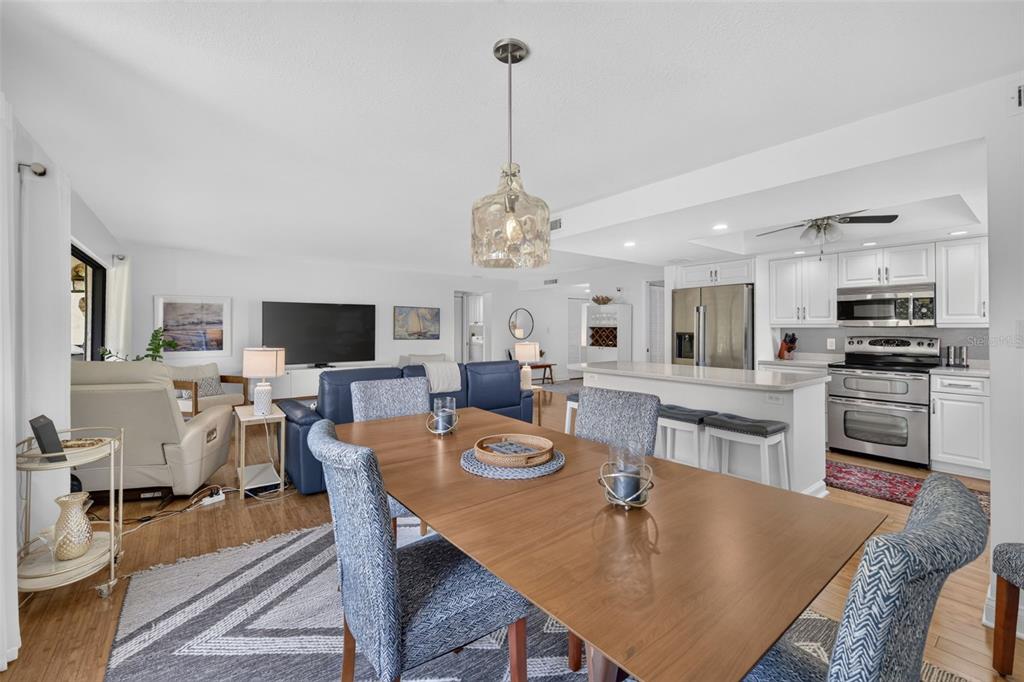 An open-concept living and dining area features a wooden table, blue sofa, and white kitchen — 1610 ISLAMORADA BOULEVARD UNIT 61B, PUNTA GORDA, FL