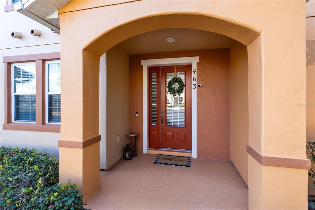 An exterior view of a covered front porch featuring a red door with a wreath — 463 ELLIS SQUARE COURT, SANFORD, FL