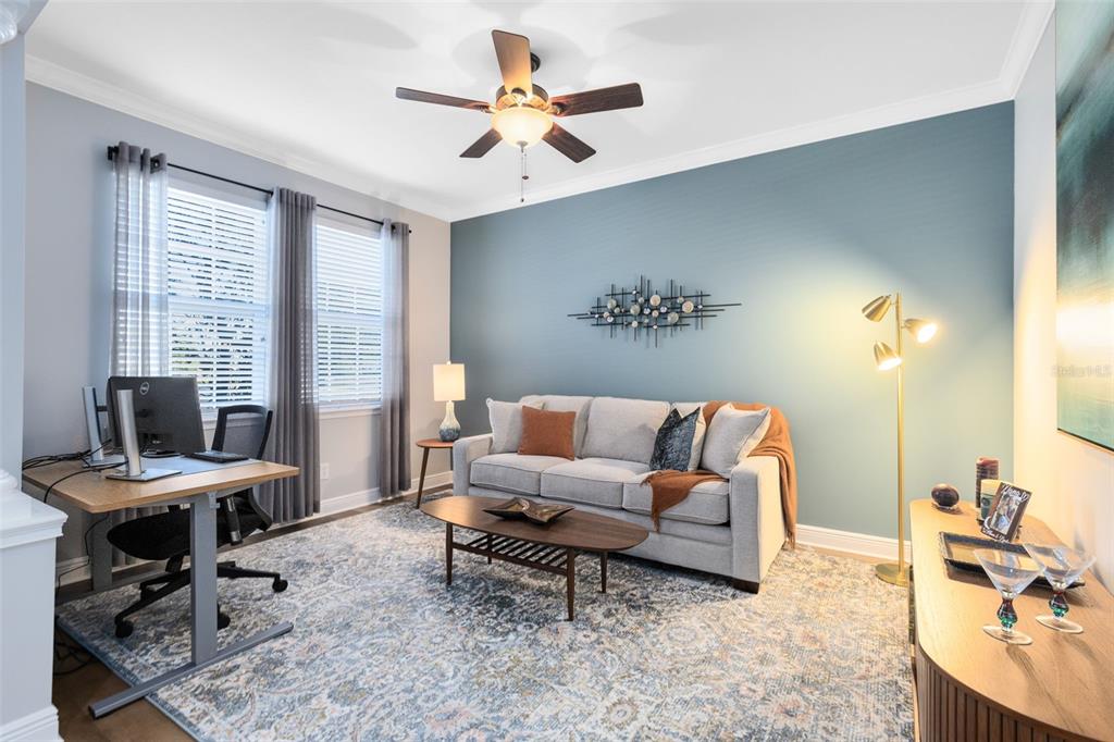 A home office with a sofa, desk, area rug, and blue accent wall — 463 ELLIS SQUARE COURT, SANFORD, FL