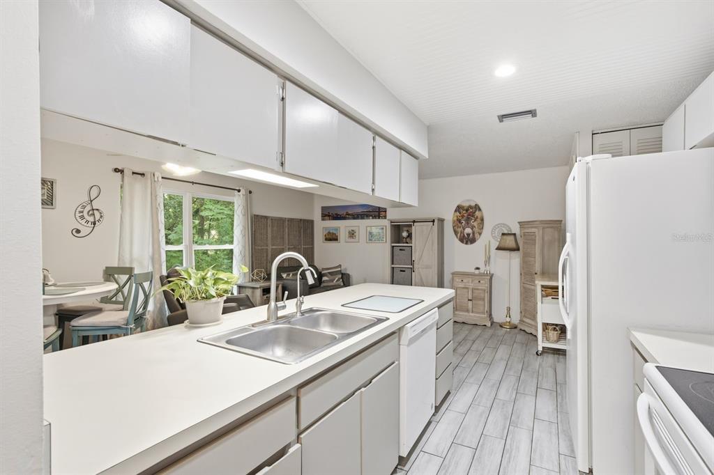 A kitchen with white cabinets, a double sink, and light-colored tile flooring — 10624 ENCINO COURT, PORT RICHEY, FL