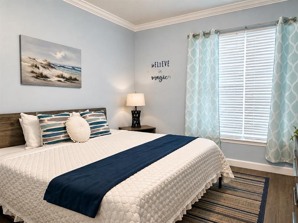 A bedroom features a bed with a white quilt, blue runner, and a coastal-themed wall painting — 1301 TUSCAN TERRACE UNIT 9205, DAVENPORT, FL