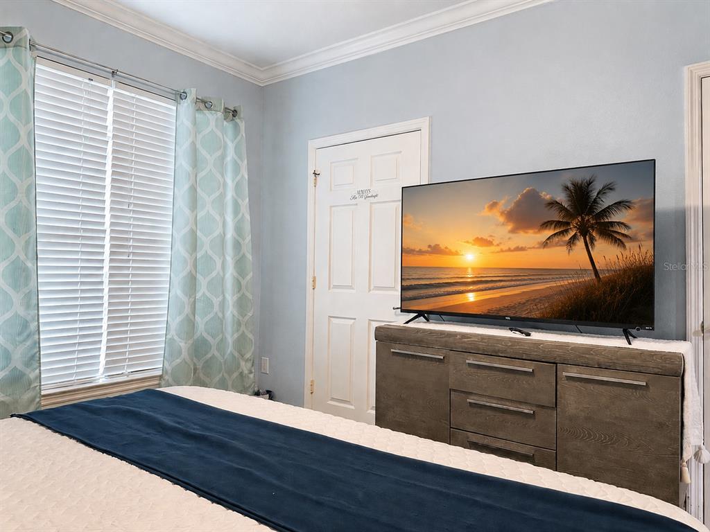 A bedroom features a bed, a dresser with a television, and a window with curtains — 1301 TUSCAN TERRACE UNIT 9205, DAVENPORT, FL