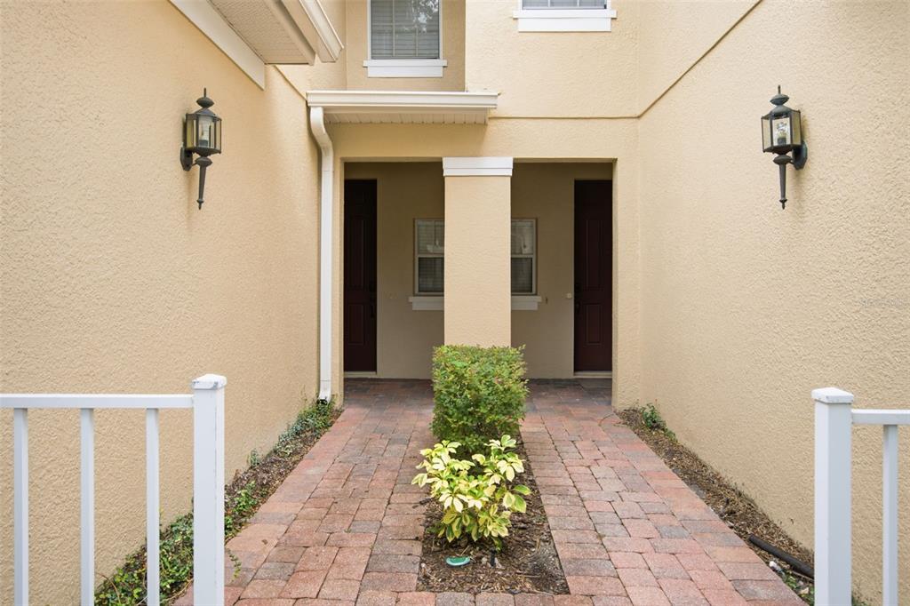 A brick walkway leads to two dark front doors under a covered entryway — 5957 STRADA CAPRI WAY, ORLANDO, FL