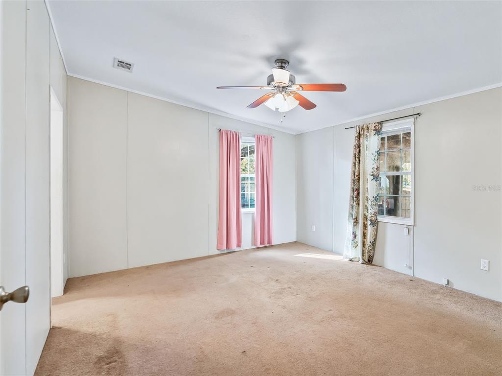 A living room with tan carpeting flows into a kitchen featuring wood cabinets and tile flooring — 3861 CR 519, COLEMAN, FL