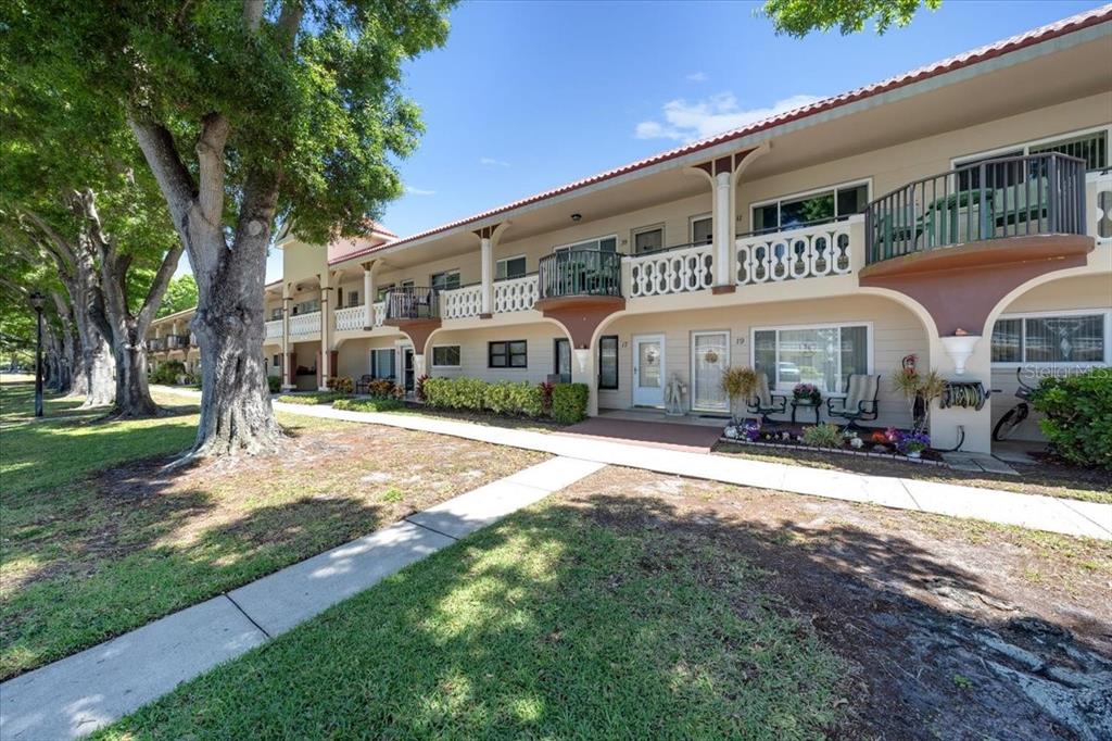 A two-story apartment building with balconies and a sidewalk surrounded by large trees — 2401 FRANCISCAN DRIVE UNIT 41, CLEARWATER, FL