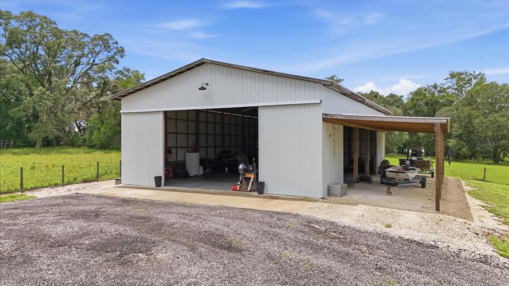 A metal-sided pole barn with a large open bay and an attached side carport — 1750 W MANSFIELD STREET, LECANTO, FL