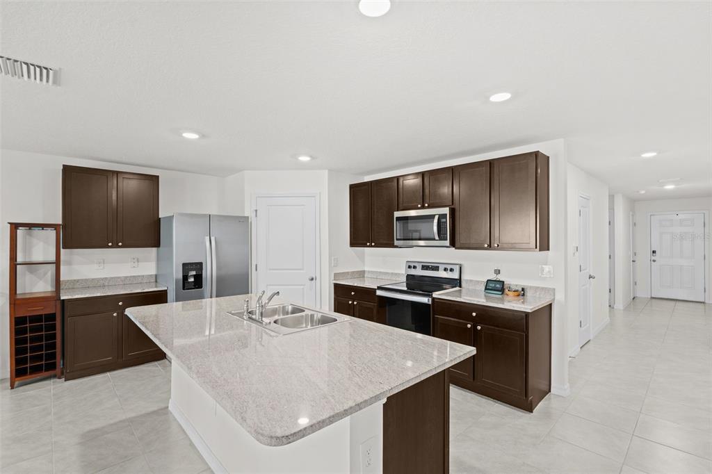 A dining area with a wooden table and chairs sits adjacent to an open kitchen — 12210 KINGSLEY TRAIL, PARRISH, FL