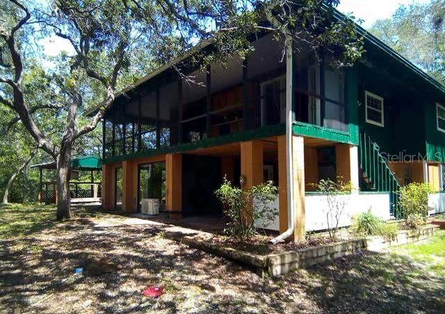 A two-story house with a screened-in upper porch and an open lower patio area — 3339 E WITHLACOOCHEE TRAIL, DUNNELLON, FL