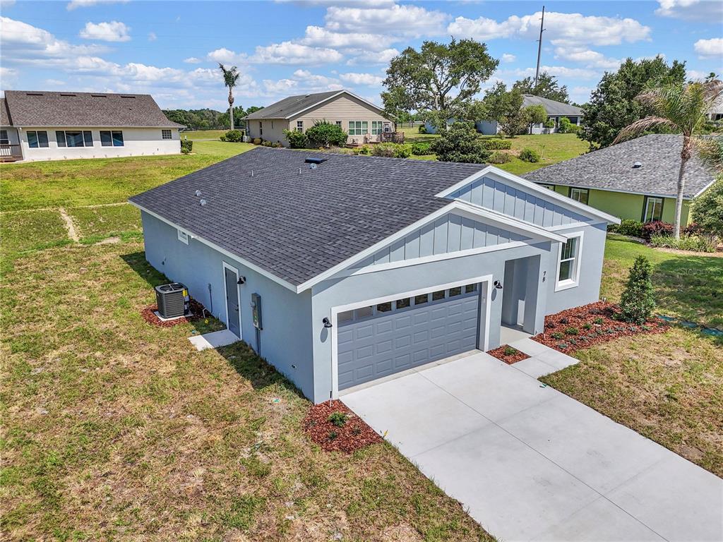 An aerial view of a single-story gray house with a two-car garage and asphalt roof — 78 FAIRWAY CIRCLE, UMATILLA, FL