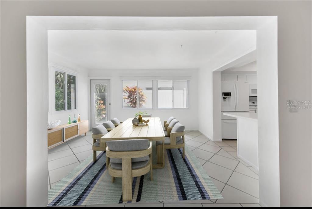 A dining room with a wooden table, gray chairs, a striped rug, and tiled floors — 3915 SCHWALBE DRIVE UNIT 128, SARASOTA, FL