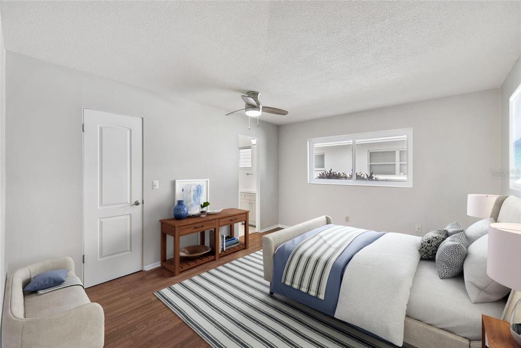 A bedroom with wood-look flooring, a ceiling fan, a bed, and a wooden console table — 3915 SCHWALBE DRIVE UNIT 128, SARASOTA, FL