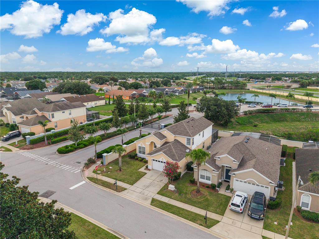 An aerial view shows two suburban houses with driveways and lawns near a small lake — 8184 FAN PALM WAY, KISSIMMEE, FL