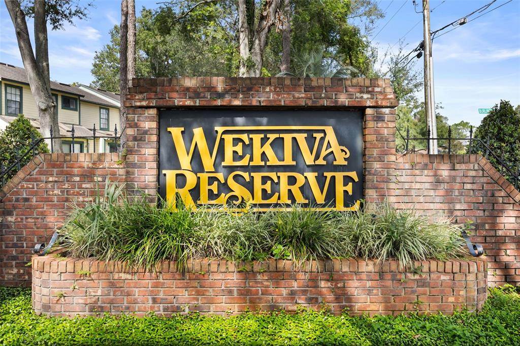 A brick monument sign with yellow lettering reads Wekiva Reserve in front of residential buildings — 2776 LANCASTER COURT, APOPKA, FL