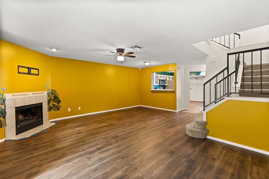 A living room with yellow walls, wood-look flooring, a fireplace, and a staircase — 2776 LANCASTER COURT, APOPKA, FL